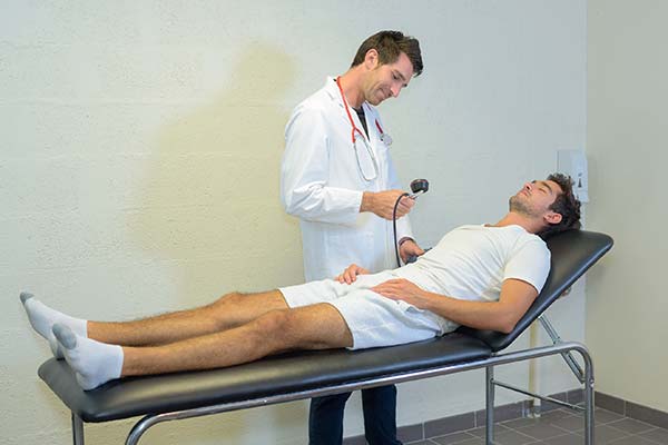 doctor in white coat examining a man wearing white