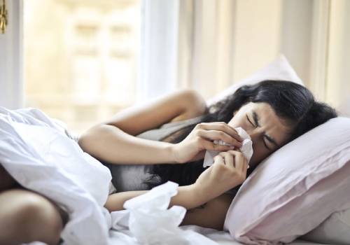 woman sneezing in bed